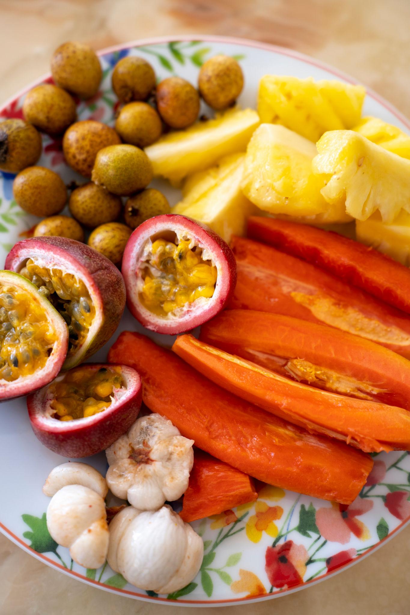 A plate of tropical fruits including papaya, pineapple and mamoncillo